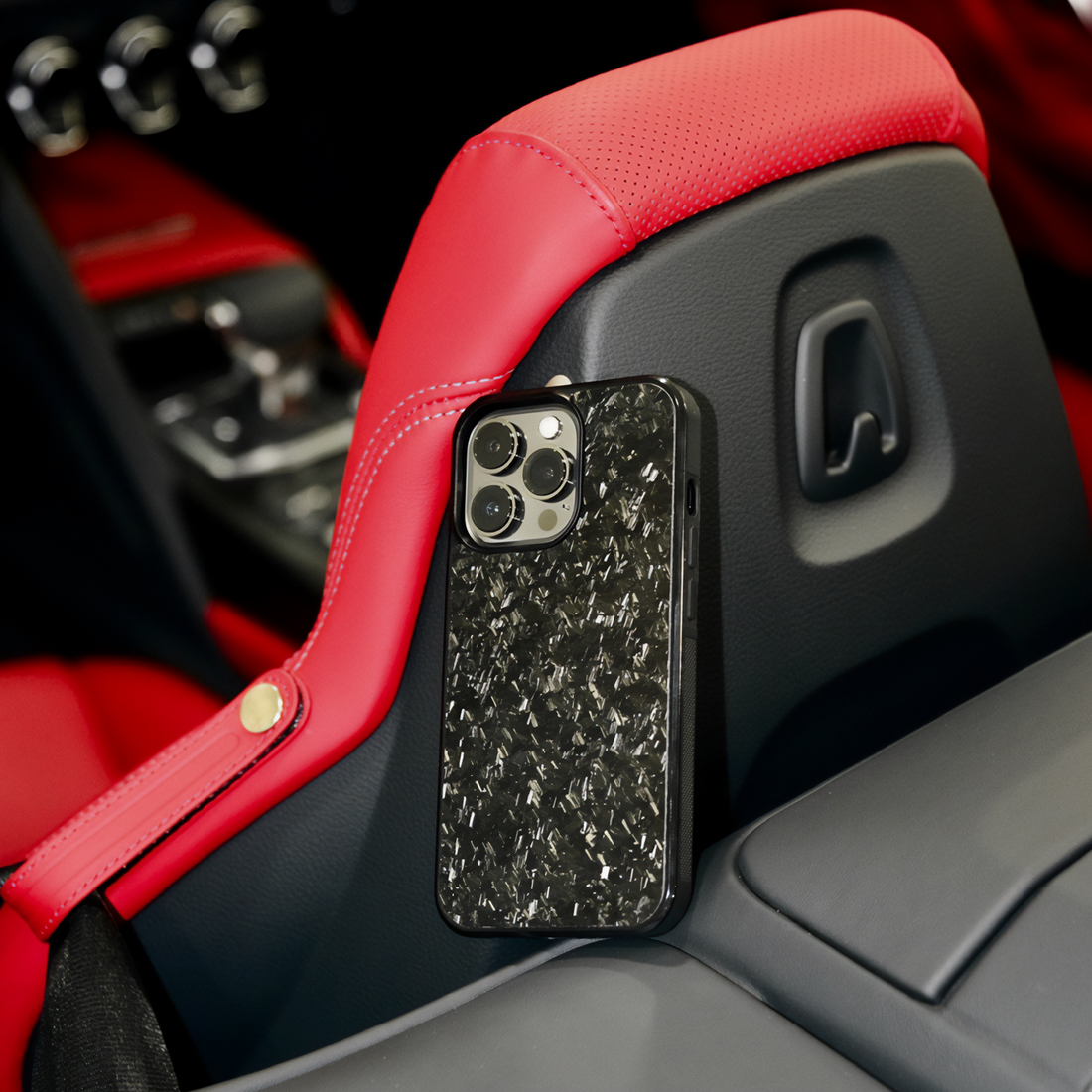Forged black iPhone case placed on red leather car seat, luxury shot
